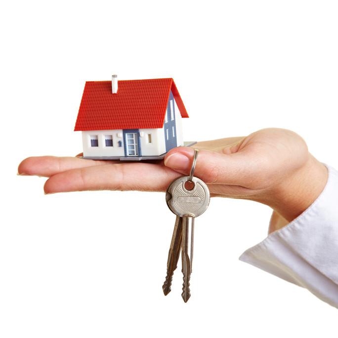 Eine Hand hält das Modell eines Hauses und einen Schlüssel