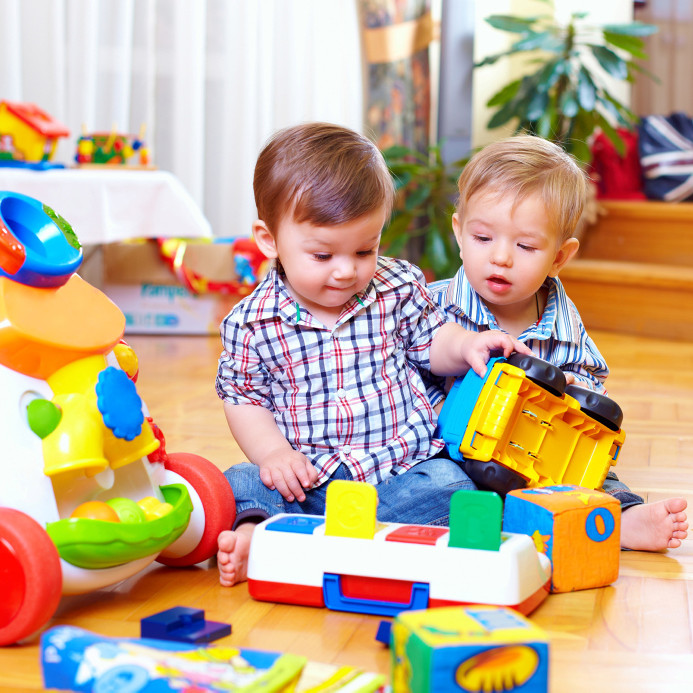 Zwei Kleinkinder spielen auf einem Fußboden