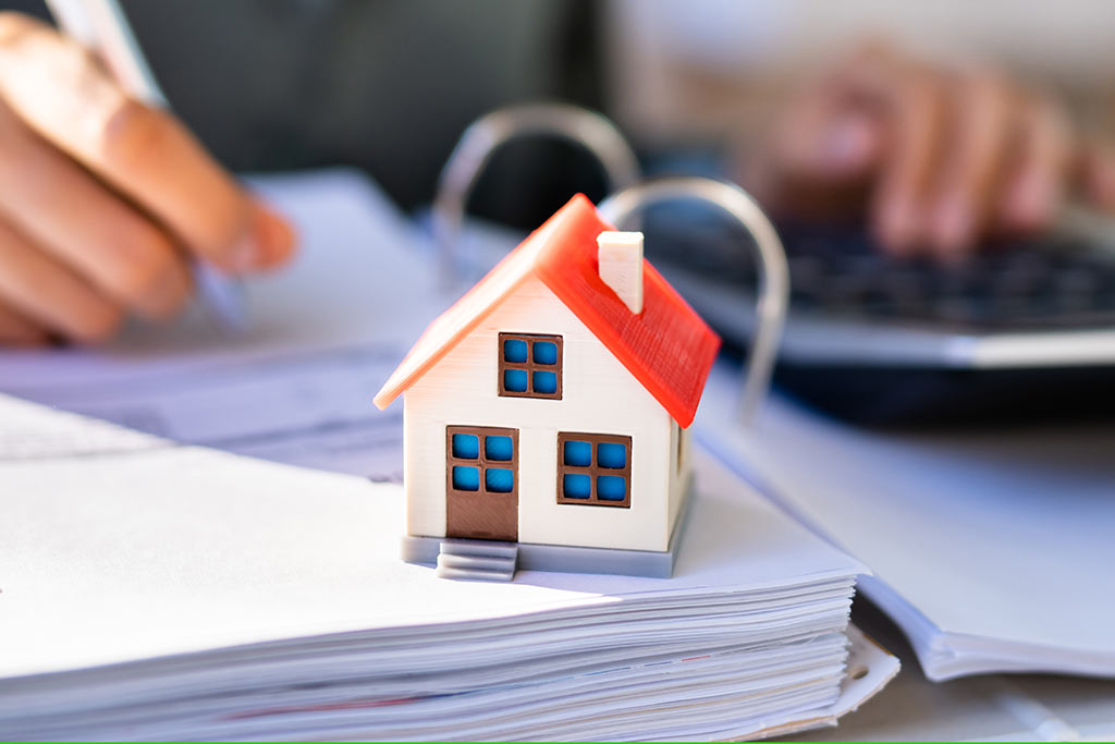 Ein Modell eines Hauses steht auf einem aufgeschlagenen Aktenordner Ein Modell eines Hauses steht auf einem aufgeschlagenen Aktenordner