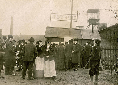 An der Trinkhalle am Zecheneingang der Zeche Radbod werden Listen der Verunglückten ausgehängt, 12. November 1908.
