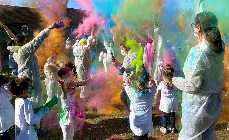 Viele Kinder werfen Farbpulver in die Luft und werden ganz bunt