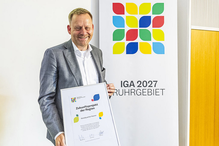 Stadtbaurat Andreas Mentz hält eine Urkunde