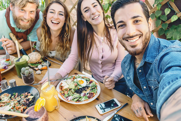 Gruppe junger Leute macht ein Selfie beim Essen im Restaurant