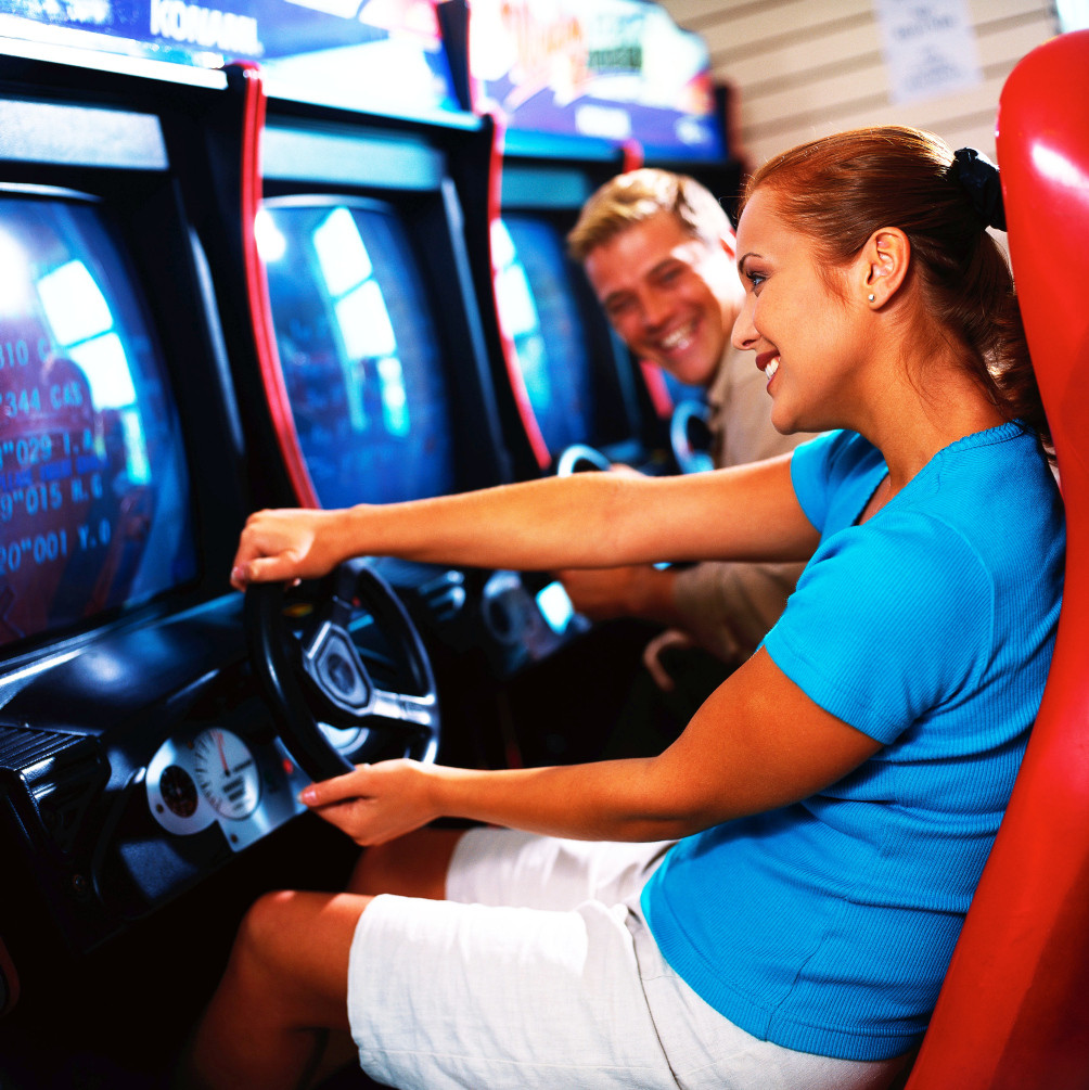 Junges Paar vergnügt sich am Fahrsimulator in einer Spielhalle