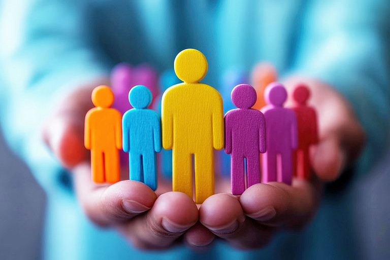 Farbenfrohe Menschenfiguren in liebevollen Händen symbolisieren Gemeinschaft, Unterstützung und den Wert jedes Einzelnen.