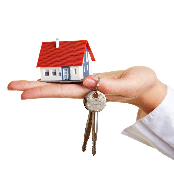 Eine Hand hält das Modell eines Hauses und einen Schlüssel