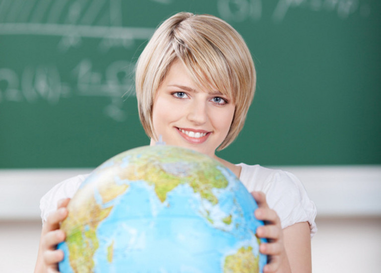 Studentin mit Globus vor einer Tafel