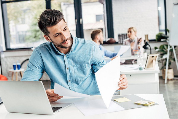 AdobeStock 229542605 Ein junger Mann sitzt an seinem Schreibtisch und arbeitet konzentriert