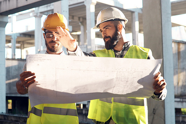 Zwei Bauingenieure schauen sich auf einer Baustelle einen Plan an