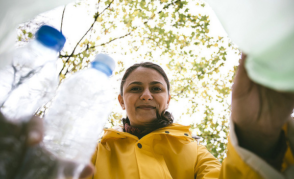Eine Frau schaut in einen Sack mit Plastikflaschen