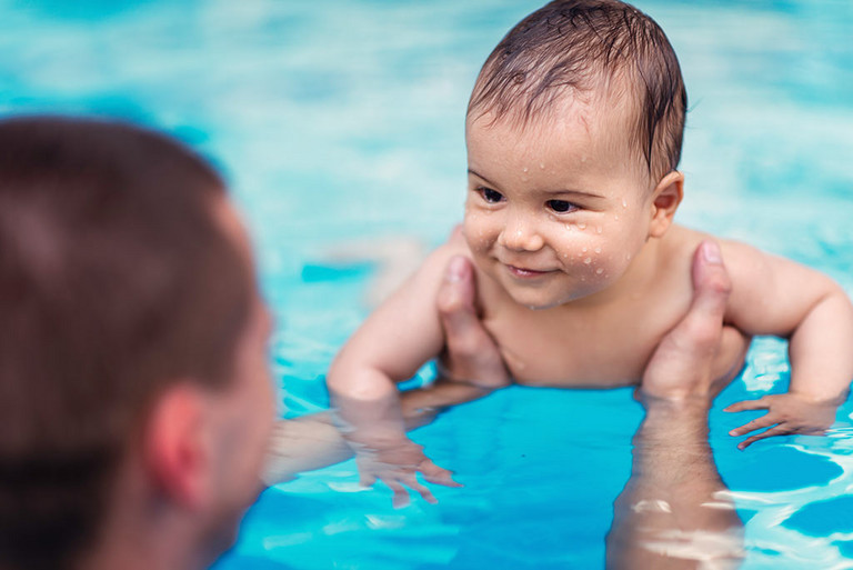 Ein Vater spielt mit seinem Baby im Schwimmbecken