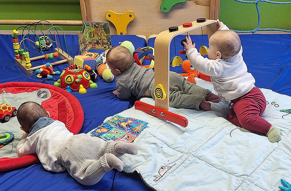 drei Säuglinge krabbeln auf einer Decke und spielen