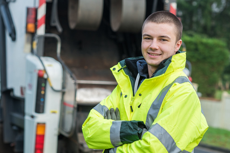 Ein Mann steht vor einem M&uuml;llfahrzeug