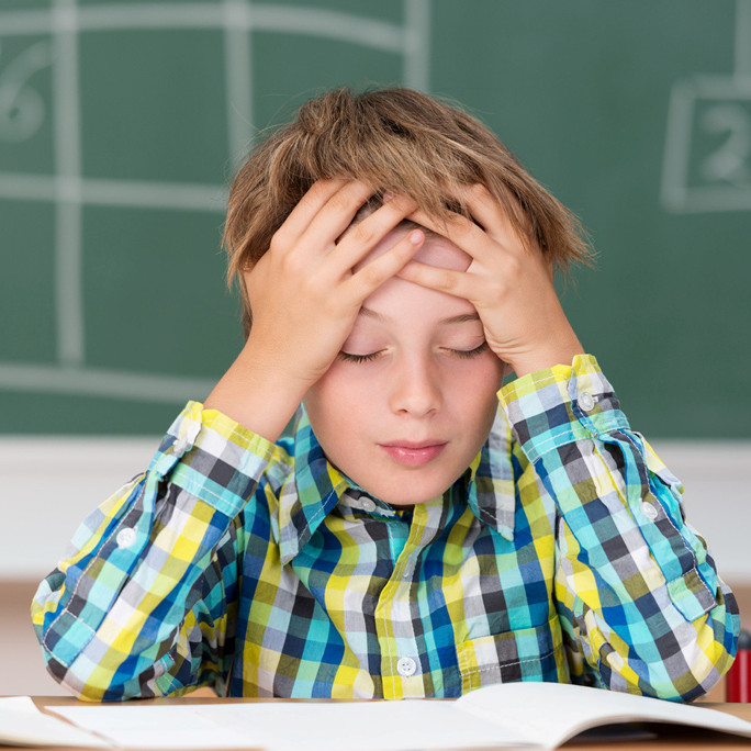 junge in der grundschule h&auml;lt sich den kopf