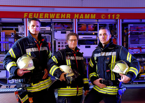 Feuerwehrleute der Stadt Hamm stehen vor einem Feuerwehrauto