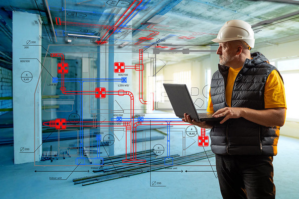 Fotomontage von einem Ingenieur mit einem Laptop der in einem Rohbau steht. Im Hintergrund sieht mal Heizungspläne.