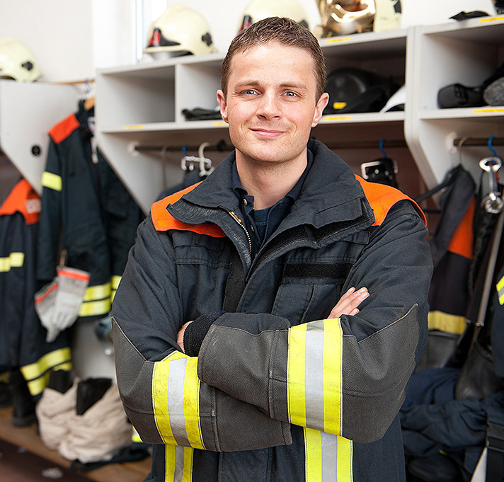 Ein junger Feuerwehrmann in Uniform in einem Umkleideraum
