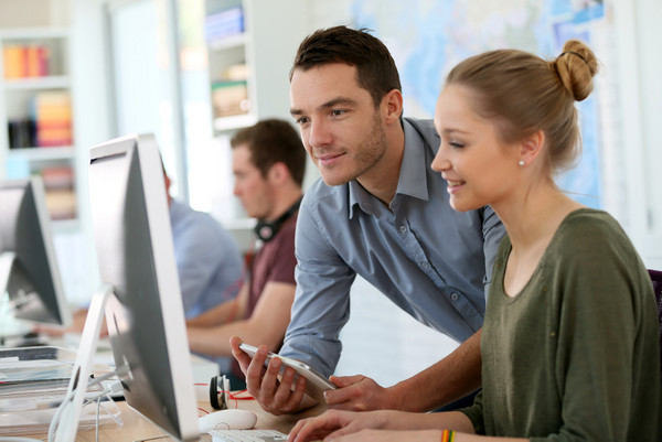AdobeStock 79638230 Ein Ausbilder erklärt einer Praktikantin etwas am Computer