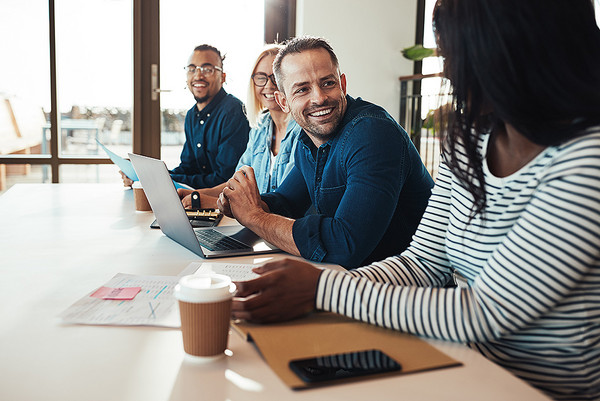 AdobeStock 260534214 Mehrere Menschen sitzen an einem Tisch und unterhalten sich über vorliegende Unterlagen