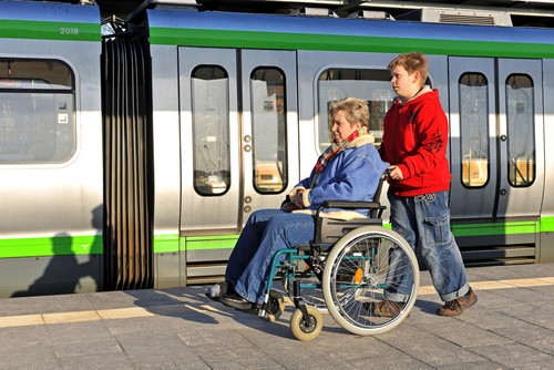 Frau im Rollstuhl auf einem Bahnsteig neben einem Zug