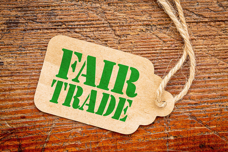 Fair-Trade-Logo auf einem Papierpreisschild vor rustikalem, rot gestrichenem Scheunenholz &ndash; Konzept f&uuml;r bewusstes Einkaufen