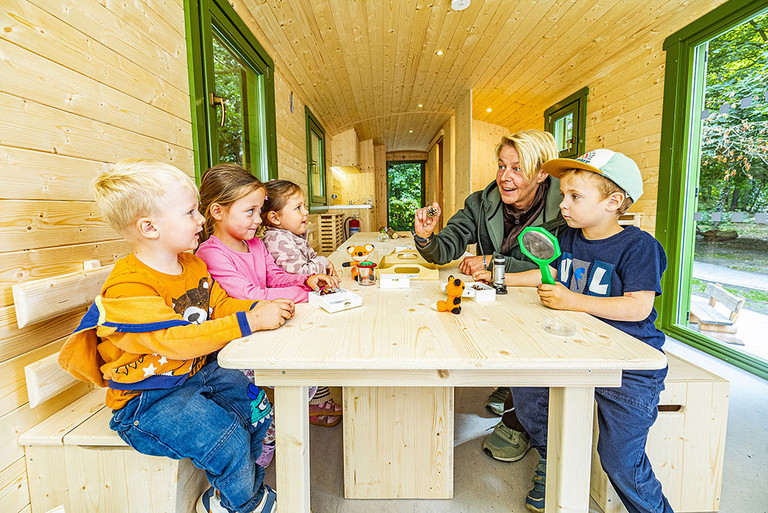 Kinder und Erzieherinnen spielen an einem Tisch im neuen Bauwagen der Kita Sylverberg