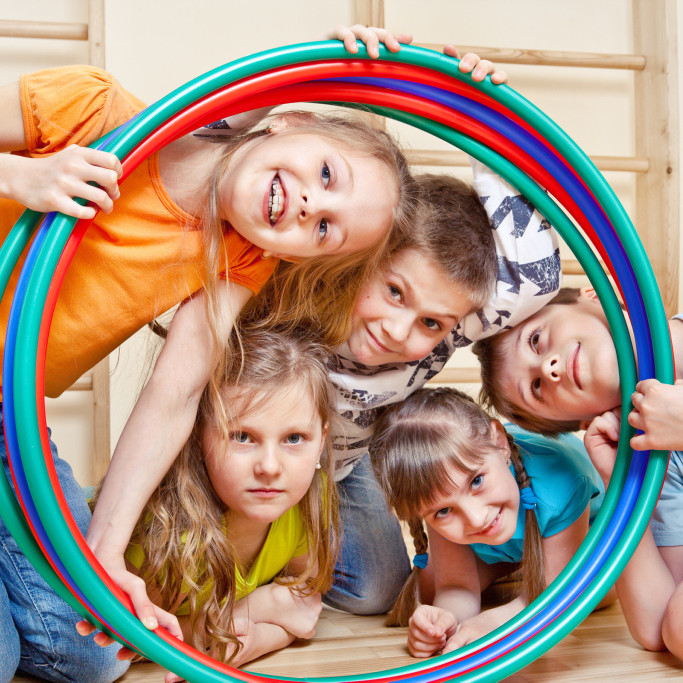 Lachende Kinder schauen durch einen Hula Hoop-Reifen