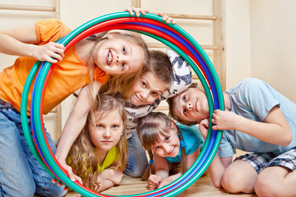 Lachende Kinder schauen durch einen Hula Hoop-Reifen