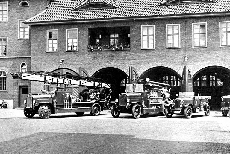 Fahrzeuge der Feuerwehr Hamm mit Motospritze und Drehleiter im Innenhof der Feuerwache, um 1930. Fahrzeuge der Feuerwehr Hamm mit Motospritze und Drehleiter im Innenhof der Feuerwache, um 1930.