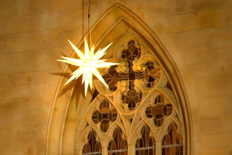 Leuchtender Stern vor einem Fenster an der Pauluskirche