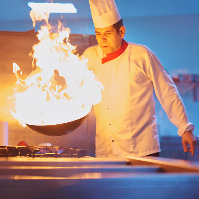 Küchenchef bereitet Nahrung im flammenden Wok zu