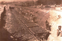 Arbeiter schaufeln Abraum in Eisenbahnloren