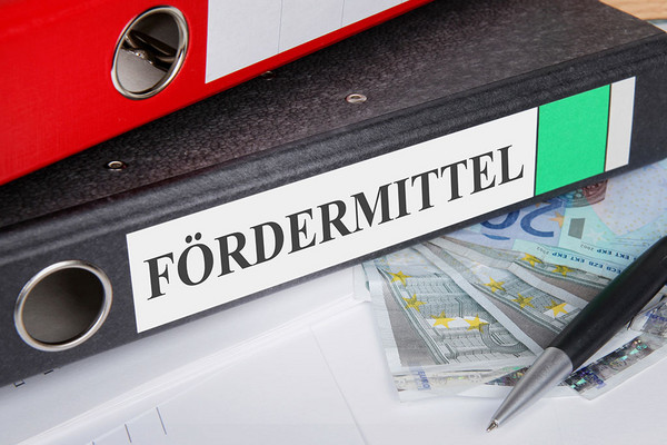 Geld und Akte mit der Aufschrift Fördermittel