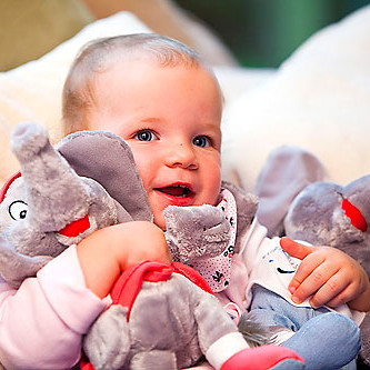 Foto zeigt ein Kleinkind mit zwei Plüschelefanten im Arm