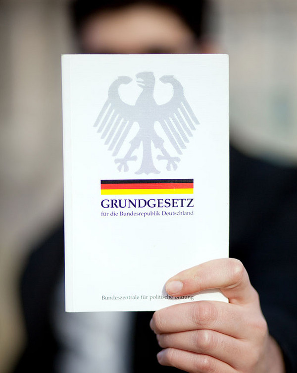 AdobeStock 31037608 männliche Hand zeigt das Grundgesetz