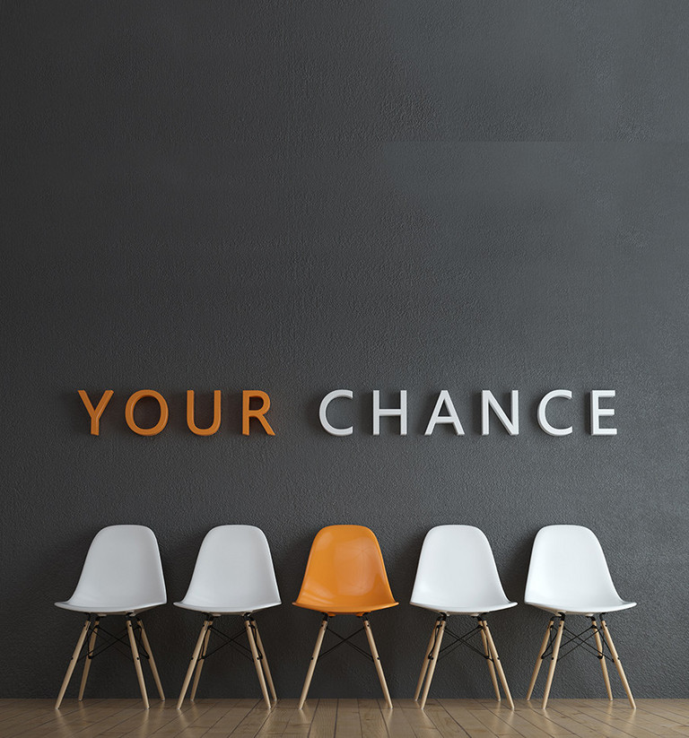 Eine Reihe weißer Stühle mit einem oragenen Stuhl in der Mitte. Darüber der Satz 'Your Chance''