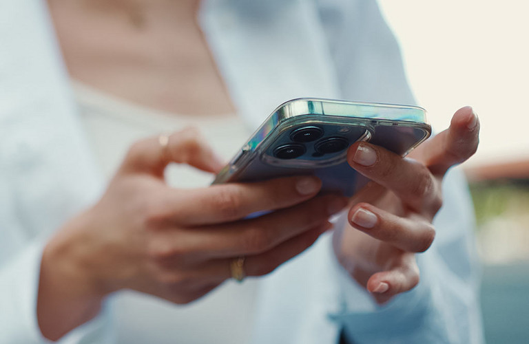 Eine Frau h&auml;lt ein Handy in der Hand.