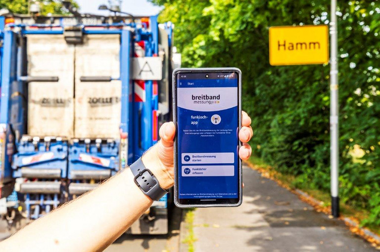 Eine Person h&auml;lt ein Handy auf dem eine App zur Breitbandmessung ge&ouml;ffnet ist