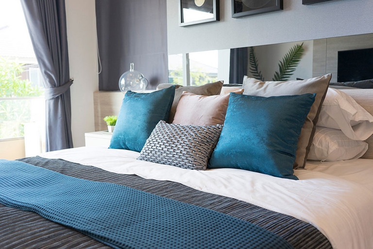 Luxuriöses Set aus blauen und grauen Kissen auf einem Bett