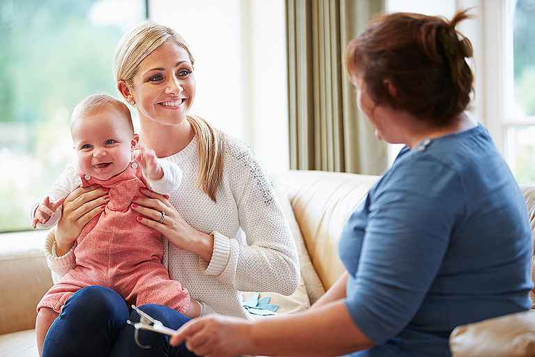 Eine Beraterin besucht eine junge Mutter mit ihrem Baby Eine Beraterin besucht eine junge Mutter mit ihrem Baby