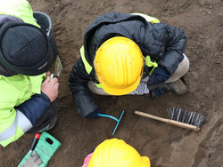 Das Bild zeigt Kinder, die unter Anleitung nach archäologischen Fundstücken graben