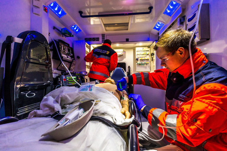 Zwei Rettungssanitäter trainieren in einem Rettungswagen an einer Puppe