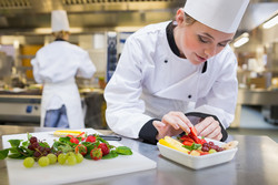 Fotolia 45643586 Chefköchin legt eine Erdbeere in den Obstsalat