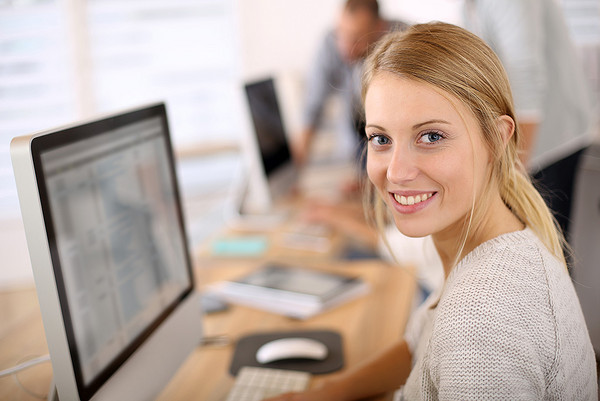 Eine junge Frau sitzt in einem Büro vor einem Computermonitor