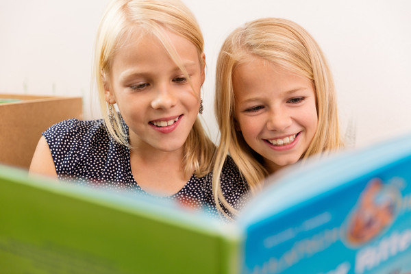 AdobeStock 141123848 zwei Mädchen lesen ein Buch