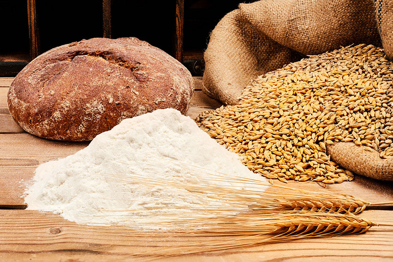 Brot mit Mehl, Getreide und &Auml;hren auf Holztisch