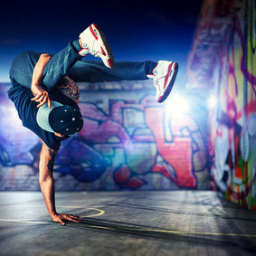 junger Mann tanzt vor bunten Graffitiwänden 