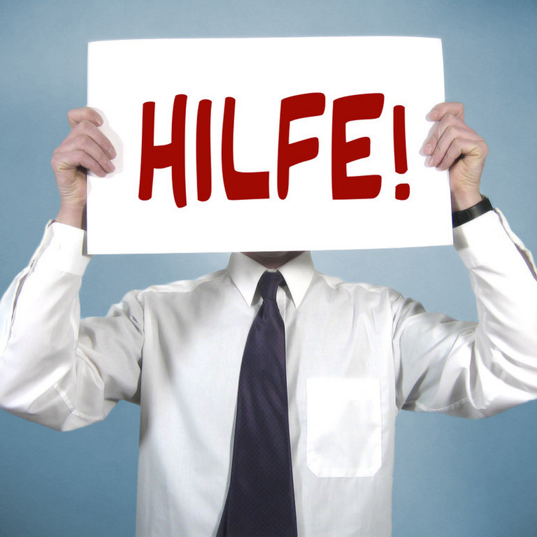 ein Mann hält sich ein Schild mit der Aufschrift Hilfe vor den Kopf 