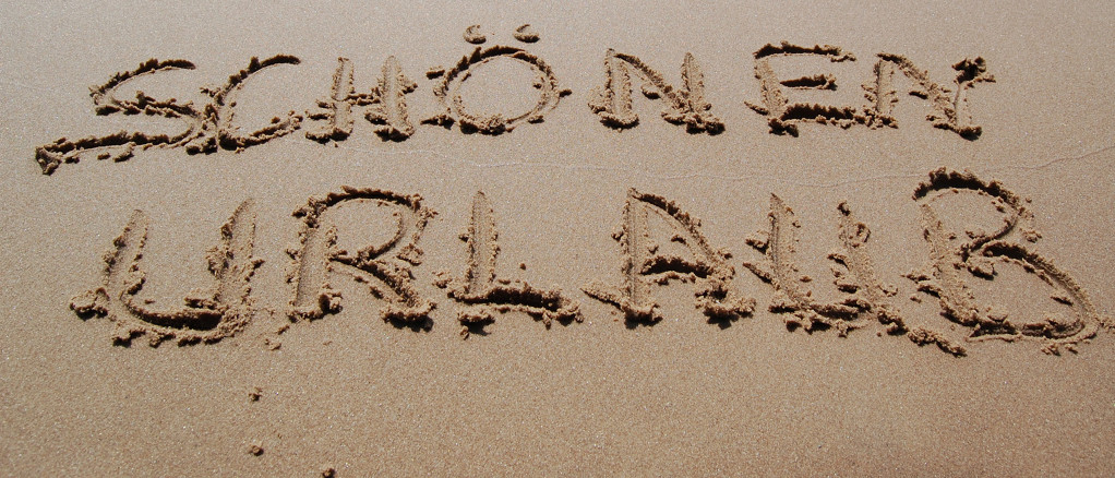 "Sch&ouml;nen Urlaub" in den Sand geschrieben