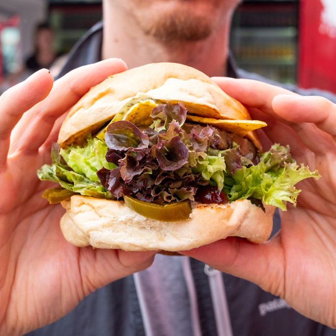 Mann hält einen veganen Burger in seinen Händen